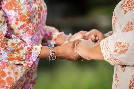 Two people holding hands in colorful attire.